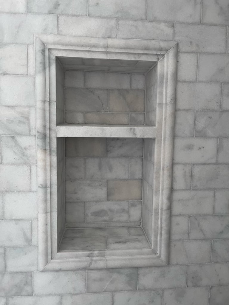 Marble subway tile wall with built-in niche shelving featuring two horizontal compartments and recessed frame
