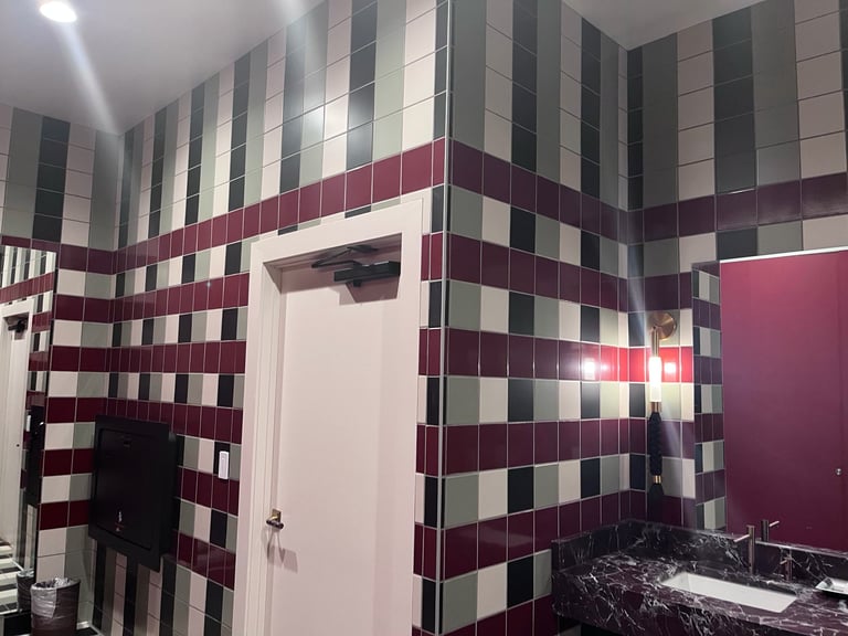 Modern bathroom with red and white checkered tile walls, white door, and black granite countertop with sink