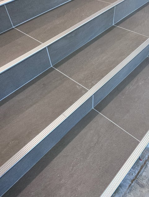 Close-up of stacked rectangular metal trays or bins with angled perspective showing metallic and gray surfaces